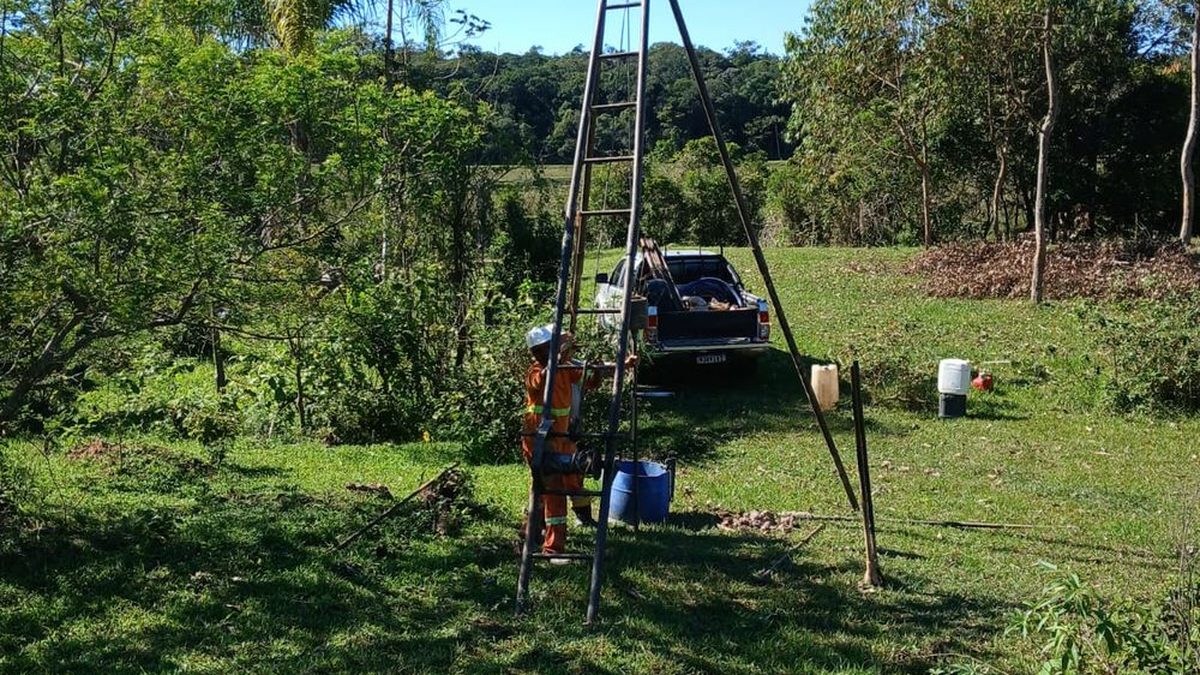 Equipe do Grupo NEV com tripé de sondagem montado em terreno de campo, ao lado da caminhonete